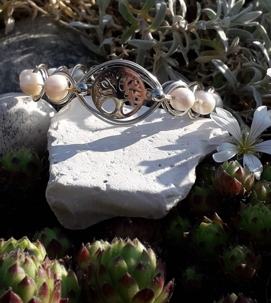 bracelet-arbre-de-vie-perles-eau-douce-mcybijoux photographie prise en extérieur sur une pierre blanche accompagnée d'une fleur