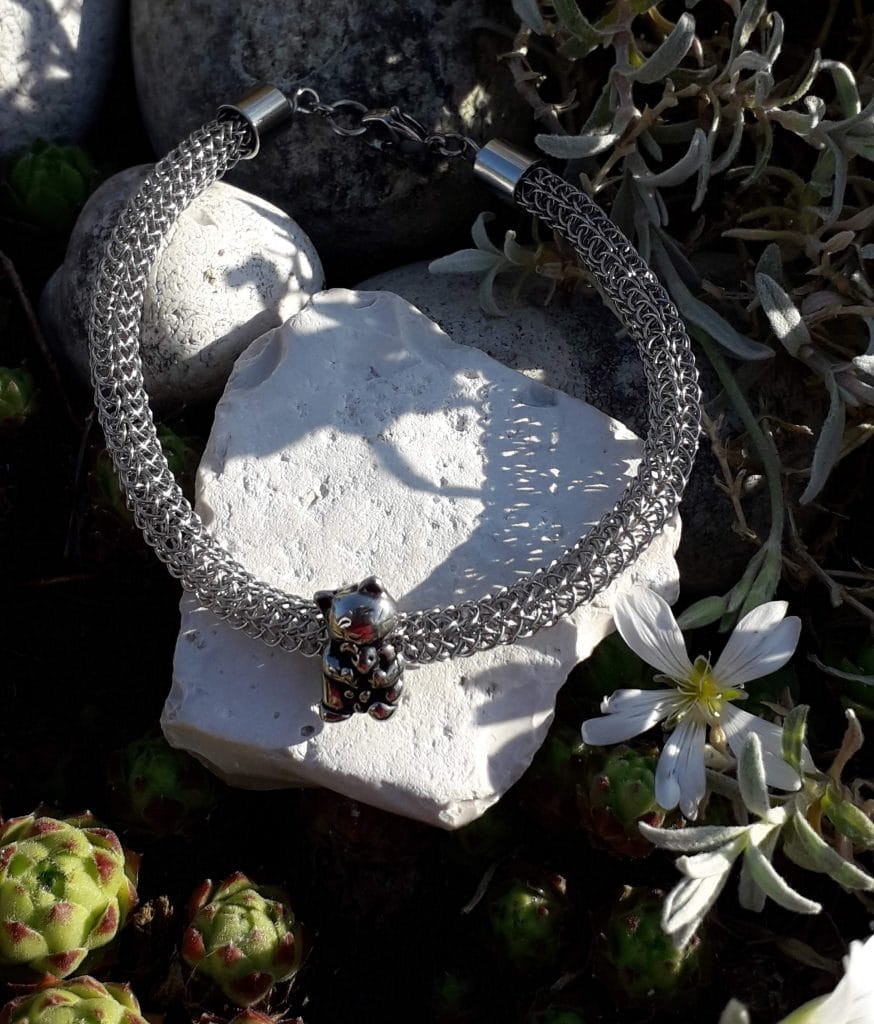 bracelet-viking-perle-ours-acier-mcybijoux-nature photographie en extérieur sur une pierre blanche à côté d'une fleur