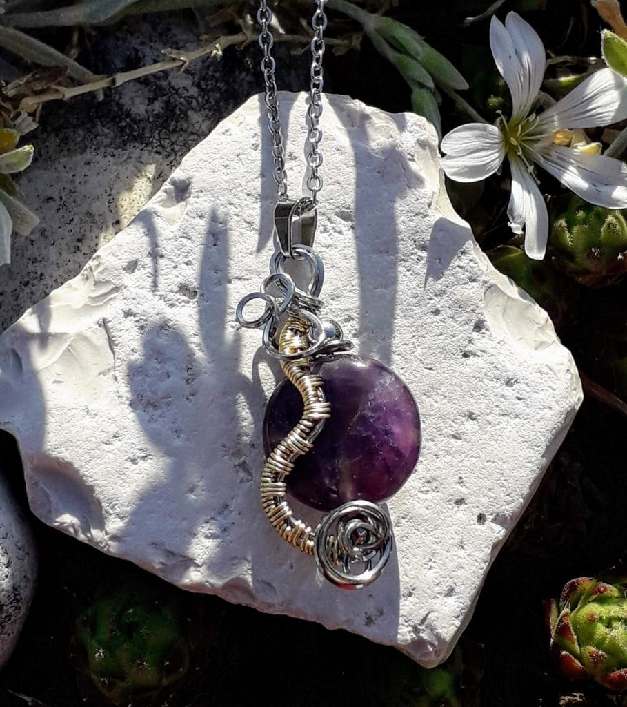 pendentif-amethyste-mcybijoux-nature photographie prise à l'extérieur sur une pierre blanche et une fleur