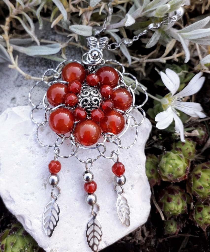 pendentif-fleur-agate-rouge-mcybijoux-nature photographie extérieure sur une pierre blanche avec une fleur