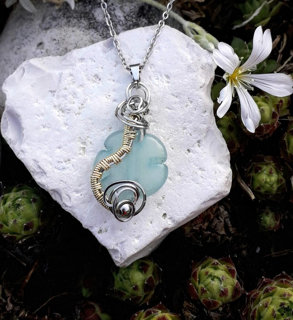 pendentif-fleur-aigue-marine-mcybijoux-nature photographie extérieure sur une pierre blanche avec une fleur