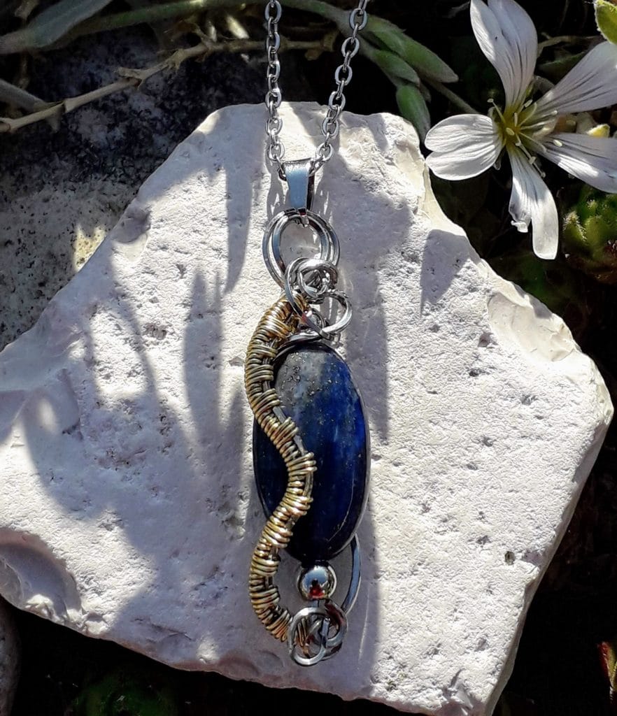pendentif-lapis-lazuli-mcybijoux-nature photographie en extérieur sur une pierre blanche avec une fleur