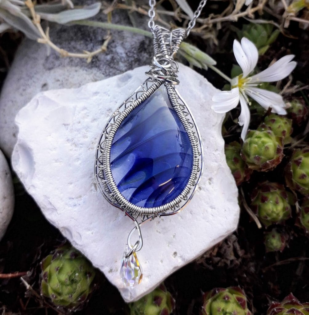 verre-murano-bleu-swarovski-mcybijoux photographie nature prise en extérieur sur une pierre blanche avec une fleur