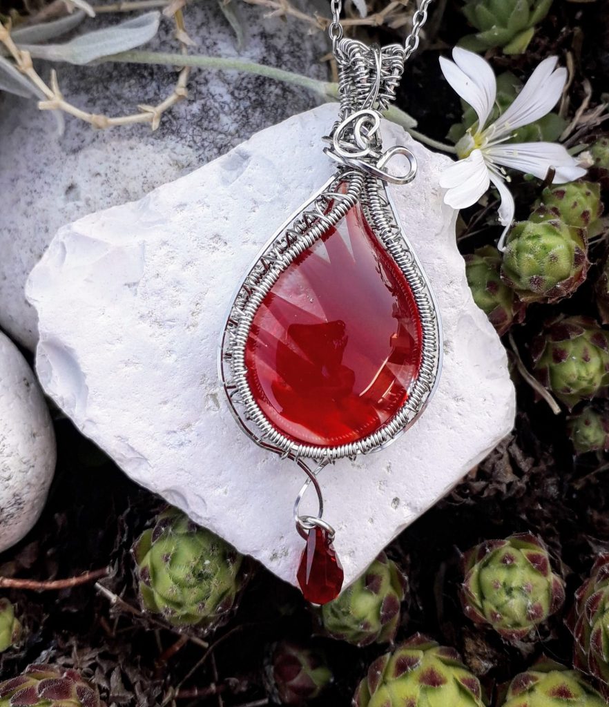 verre-murano-rouge-swarovski-mcybijoux-nature photographie prise en extérieur sur une pierre blanche avec une fleur